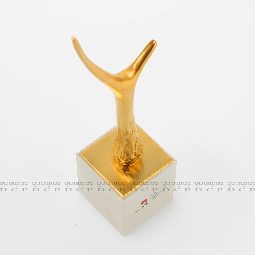 Close-up of the intricate details of a gold-plated brass trophy, showcasing a smooth finish and polished craftsmanship