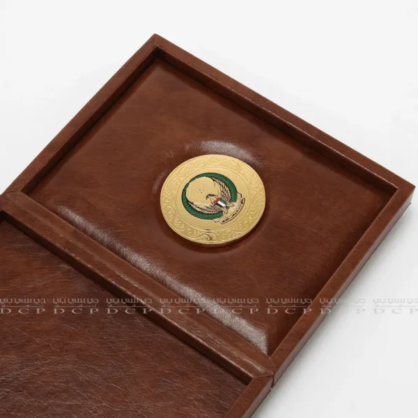 Close-up of the gold-plated brass logo on a luxury leather box, showcasing intricate craftsmanship